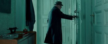 Movie still from “Unknown” (2011), directed by Jaume Collet-Serra – An older man in a hat and coat opening a door; Medium shot, Low angle