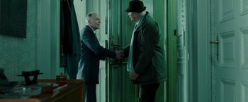 Movie still from “Unknown” (2011), directed by Jaume Collet-Serra – Two older men shaking hands in front of green doors; Medium shot, Over the shoulder angle