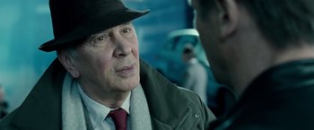 Movie still from “Unknown” (2011), directed by Jaume Collet-Serra – An older man wearing a hat and a coat; Close Up shot, Over the shoulder angle