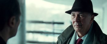 Movie still from “Unknown” (2011), directed by Jaume Collet-Serra – An older man wearing a black hat and a green jacket; Close Up shot, Over the shoulder angle