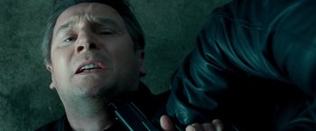 Movie still from “Unknown” (2011), directed by Jaume Collet-Serra – A man holding a gun while wearing a leather jacket; Close Up shot, Overhead angle
