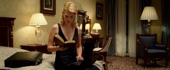 Movie still from “Unknown” (2011), directed by Jaume Collet-Serra – A beautiful blonde woman sitting on top of a bed reading; Medium shot, Low angle