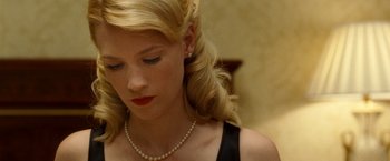 Movie still from “Unknown” (2011), directed by Jaume Collet-Serra – A woman with blonde hair wearing a black dress and pearls; Close Up shot, Low angle