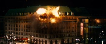 Movie still from “Unknown” (2011), directed by Jaume Collet-Serra – A large building with a large amount of smoke coming out of it; Extreme Wide shot, Low angle
