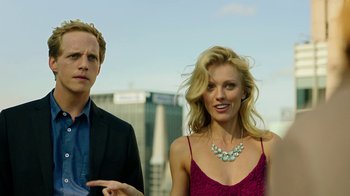 Movie still from “Urge” (2016), directed by Aaron Kaufman – A man and a woman standing next to each other; Medium shot, Low angle