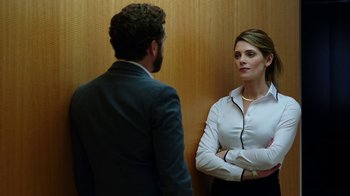 Movie still from “Urge” (2016), directed by Aaron Kaufman – A man and a woman standing next to each other in front of a wall; Medium shot, Over the shoulder angle