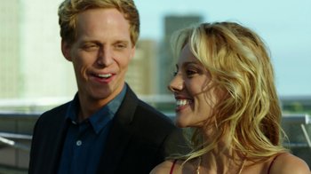 Movie still from “Urge” (2016), directed by Aaron Kaufman – A man and a woman smiling for the camera; Close Up shot, Over the shoulder angle