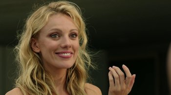 Movie still from “Urge” (2016), directed by Aaron Kaufman – A beautiful blonde woman with a smile on her face; Close Up shot, Over the shoulder angle