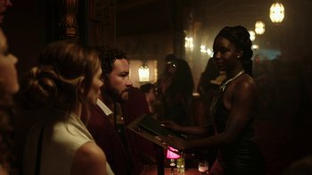 Movie still from “Urge” (2016), directed by Aaron Kaufman – A group of people sitting at a table with drinks; Medium shot, Over the shoulder angle