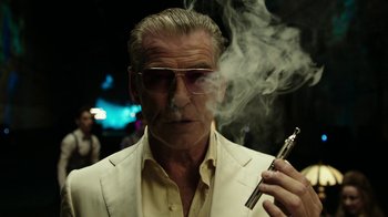 Movie still from “Urge” (2016), directed by Aaron Kaufman – An older man smoking a cigarette while wearing a suit and sunglasses; Close Up shot, Low angle
