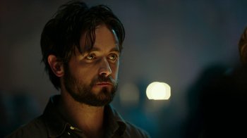 Movie still from “Urge” (2016), directed by Aaron Kaufman – A person with a beard; Close Up shot, Over the shoulder angle