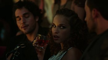 Movie still from “Urge” (2016), directed by Aaron Kaufman – A beautiful young lady holding a glass of wine; Close Up shot, Over the shoulder angle