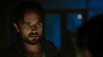 Movie still from “Urge” (2016), directed by Aaron Kaufman – A person with a beard; Close Up shot, Over the shoulder angle