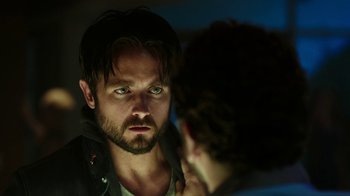 Movie still from “Urge” (2016), directed by Aaron Kaufman – A person looking at a mirror; Close Up shot, Over the shoulder angle