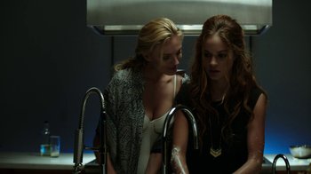 Movie still from “Urge” (2016), directed by Aaron Kaufman – Two young women in a kitchen looking at a faucet; Medium shot, Over the shoulder angle