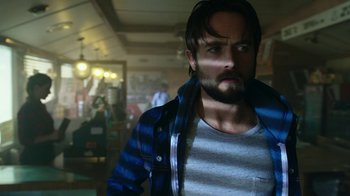 Movie still from “Urge” (2016), directed by Aaron Kaufman – A man with a beard and a striped shirt; Close Up shot, Low angle