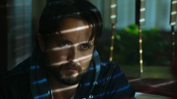 Movie still from “Urge” (2016), directed by Aaron Kaufman – A person with a beard; Close Up shot, Over the shoulder angle