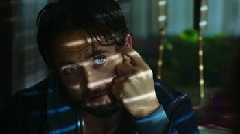 Movie still from “Urge” (2016), directed by Aaron Kaufman – A person holding a cell phone up to their face; Close Up shot, High angle