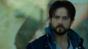 Movie still from “Urge” (2016), directed by Aaron Kaufman – A person with a beard; Close Up shot, Over the shoulder angle