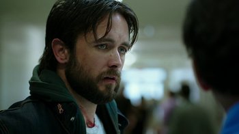 Movie still from “Urge” (2016), directed by Aaron Kaufman – A person with a beard; Close Up shot, Over the shoulder angle