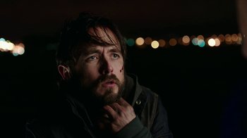 Movie still from “Urge” (2016), directed by Aaron Kaufman – A person with his hand under his chin; Close Up shot, Low angle