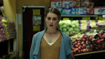 Movie still from “Urge” (2016), directed by Aaron Kaufman – A woman standing in front of fruits and vegetables; Close Up shot, Over the shoulder angle