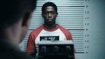 Movie still from “Snowfall” (2017), directed by Hiro Murai – A man in a red and white shirt is in front of a white wall; Close Up shot, Low angle