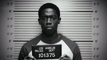 Movie still from “Snowfall” (2017), directed by Hiro Murai – A black and white photo of a man holding up a police sign; Close Up shot, Overhead angle