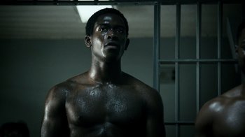 Movie still from “Snowfall” (2017), directed by Hiro Murai – A man standing in front of a jail cell; Medium shot, Low angle