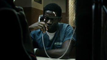 Movie still from “Snowfall” (2017), directed by Hiro Murai – A man sitting at a table talking on a phone; Close Up shot, High angle
