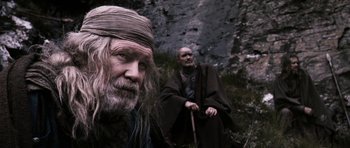 Movie still from “Valhalla Rising” (2009), directed by Nicolas Winding Refn – A man with long hair and a beard is standing next to another man with long hair and a beard; Close Up shot, Low angle