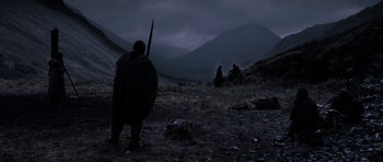 Movie still from “Valhalla Rising” (2009), directed by Nicolas Winding Refn – A man with a spear in a field with mountains in the background; Wide shot, Low angle
