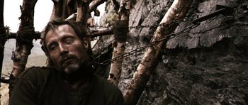 Movie still from “Valhalla Rising” (2009), directed by Nicolas Winding Refn – A man standing next to a tree with a chain around his neck; Close Up shot, Low angle
