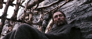 Movie still from “Valhalla Rising” (2009), directed by Nicolas Winding Refn – A person near a tree branch; Close Up shot, Low angle