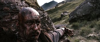 Movie still from “Valhalla Rising” (2009), directed by Nicolas Winding Refn – A man with a beard and a face tattoo on his arm; Close Up shot, Low angle