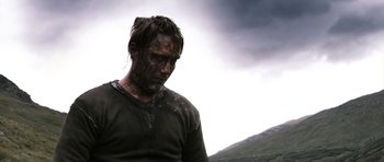 Movie still from “Valhalla Rising” (2009), directed by Nicolas Winding Refn – A man in a green t - shirt is covered in mud; Close Up shot, Low angle