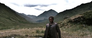 Movie still from “Valhalla Rising” (2009), directed by Nicolas Winding Refn – A man standing in the middle of a grassy field; Wide shot, Over the shoulder angle