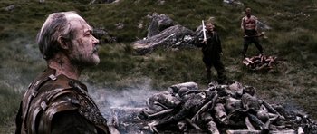 Movie still from “Valhalla Rising” (2009), directed by Nicolas Winding Refn – A man standing next to another man holding a sword; Medium shot, Over the shoulder angle
