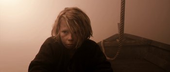 Movie still from “Valhalla Rising” (2009), directed by Nicolas Winding Refn – A young person with long hair and a black jacket; Close Up shot, High angle