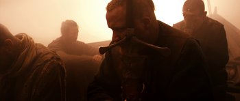 Movie still from “Valhalla Rising” (2009), directed by Nicolas Winding Refn – A man with a knife in his mouth; Close Up shot, Over the shoulder angle