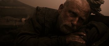 Movie still from “Valhalla Rising” (2009), directed by Nicolas Winding Refn – An old man with a beard is laying on a couch; Close Up shot, High angle