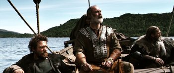 Movie still from “Valhalla Rising” (2009), directed by Nicolas Winding Refn – An old man sitting in a boat on the water; Medium shot, Low angle