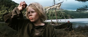 Movie still from “Valhalla Rising” (2009), directed by Nicolas Winding Refn – A young boy in a pirate costume next to a boat; Close Up shot, Low angle