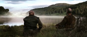 Movie still from “Valhalla Rising” (2009), directed by Nicolas Winding Refn – A man sitting in a field near a body of water; Wide shot, Low angle