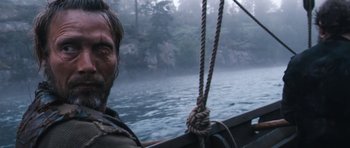 Movie still from “Valhalla Rising” (2009), directed by Nicolas Winding Refn – A man on a sailboat in the water; Close Up shot, Low angle