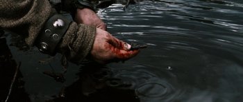 Movie still from “Valhalla Rising” (2009), directed by Nicolas Winding Refn – A person holding a fish in their hand; Extreme Close Up shot, High angle