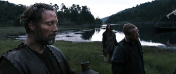 Movie still from “Valhalla Rising” (2009), directed by Nicolas Winding Refn – A group of people standing next to a body of water; Medium shot, Over the shoulder angle