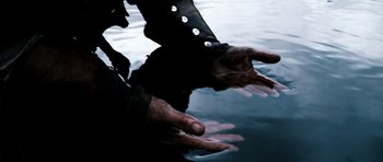 Movie still from “Valhalla Rising” (2009), directed by Nicolas Winding Refn – A person in a black jacket is in the water; Extreme Close Up shot, High angle