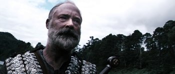 Movie still from “Valhalla Rising” (2009), directed by Nicolas Winding Refn – An old man with a beard and a pipe in his mouth; Close Up shot, Low angle