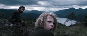 Movie still from “Valhalla Rising” (2009), directed by Nicolas Winding Refn – A young boy with blonde hair standing on top of a hill; Medium shot, Low angle